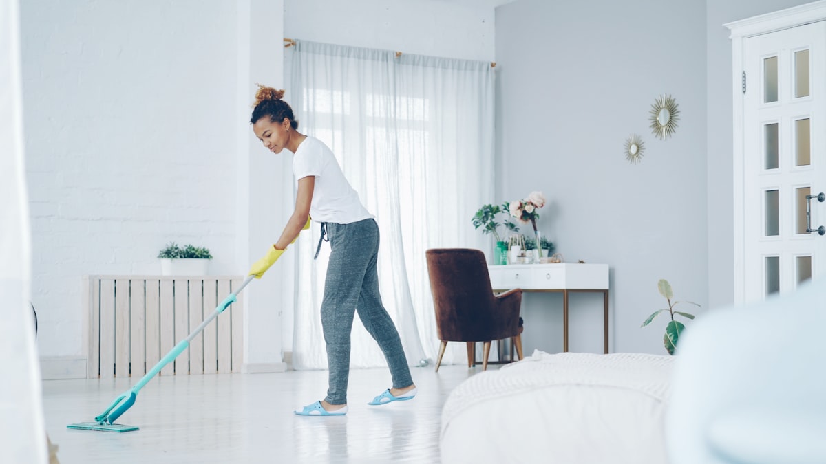 Cleana crew member mopping a bright bedroom