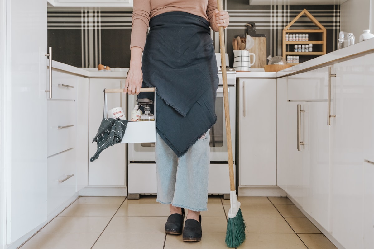 Cleaner with broom and supply caddy in a kitchen